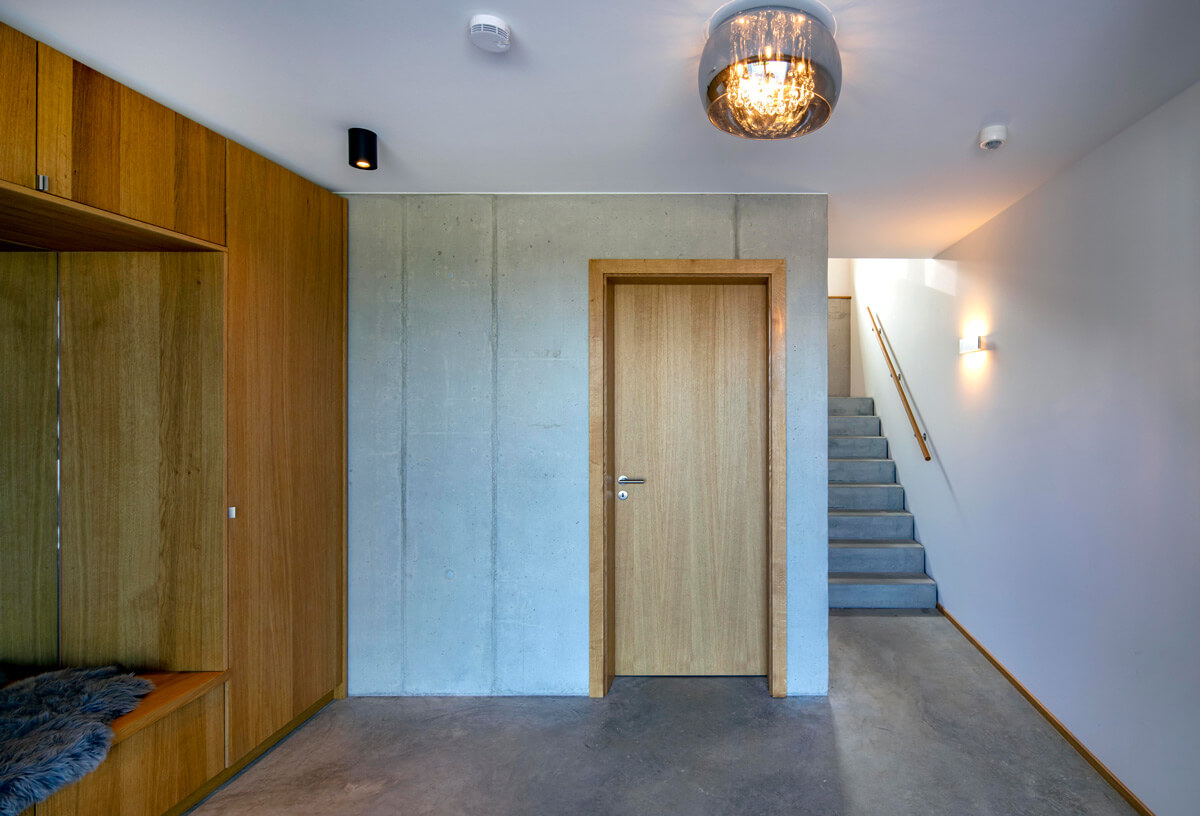 Moderner Flur in einem Holzhaus in Rimsting mit eleganter Holztür, Treppe und stilvoller Beleuchtung.