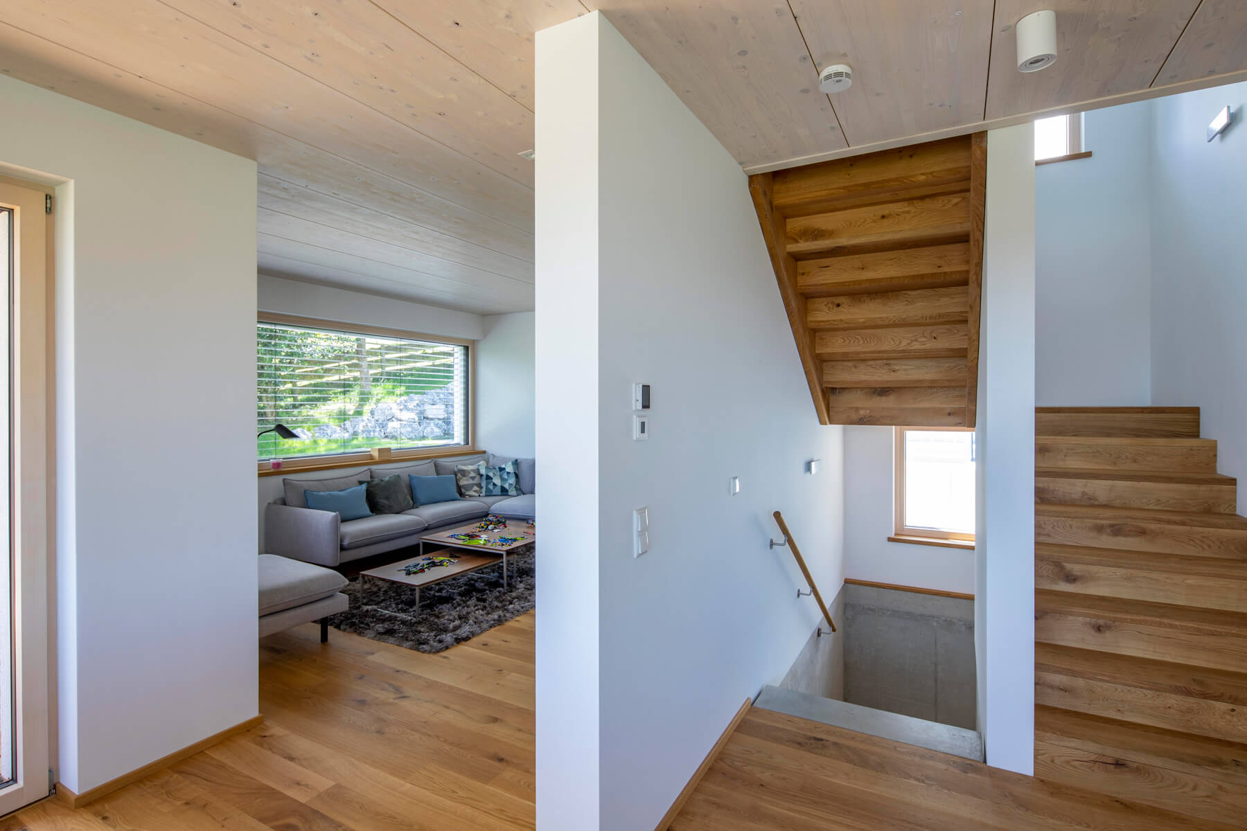 Ein moderner Wohnbereich in einem Holzhaus in Rimsting mit einem gemütlichen Sofa und einer eleganten Holztreppe.