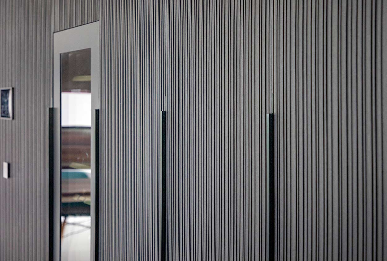 Eine moderne Wandverkleidung mit vertikalen Streifen und Glaseinsatz verleiht dem Raum ein elegantes Design.