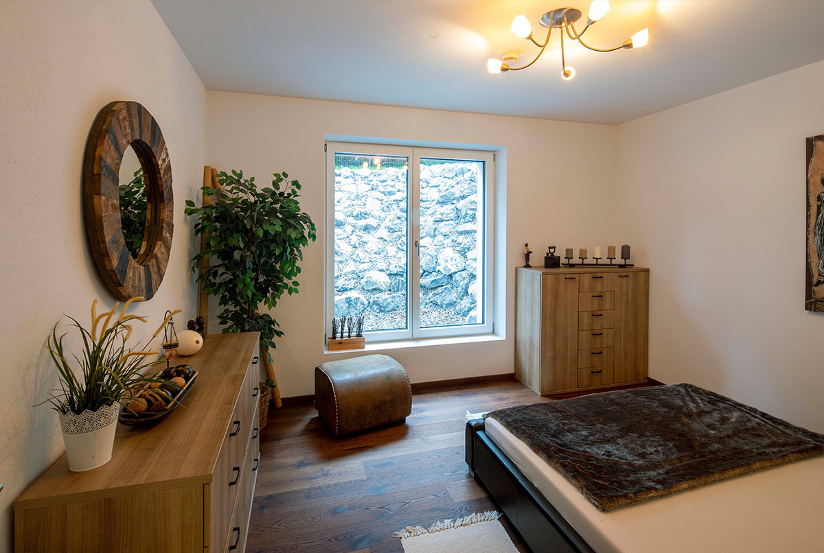 Gemütliches Gästezimmer im Energiesparhaus bei München, mit modernem Dekor, Holzmöbeln und einem großen, hellen Fenster.