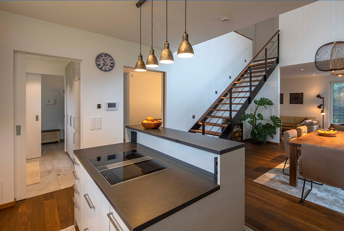 Moderne Küche in einem energiesparenden Haus nahe München mit stilvollen Hängelampen und offener Wohnbereichsarchitektur.