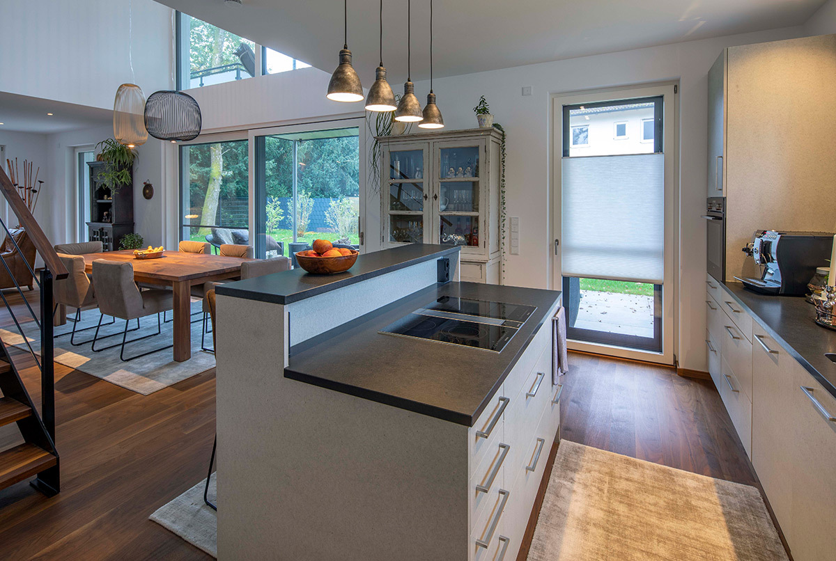 Moderne Küche mit Kochinsel in einem energiesparenden Haus im Kreis München, das nahtlos in den Essbereich übergeht.