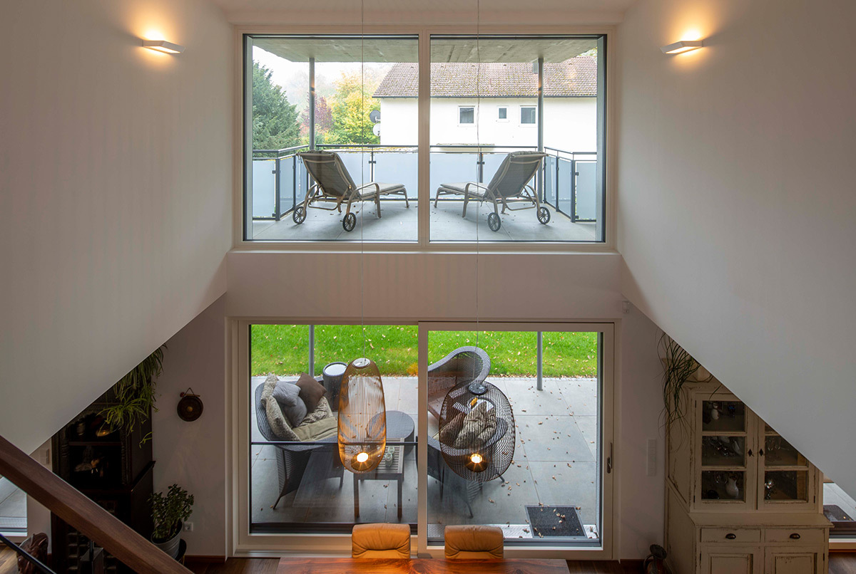 Ein modernes Energiesparhaus bei München bietet durch große Fenster einen Blick auf die Terrasse und den grünen Garten.