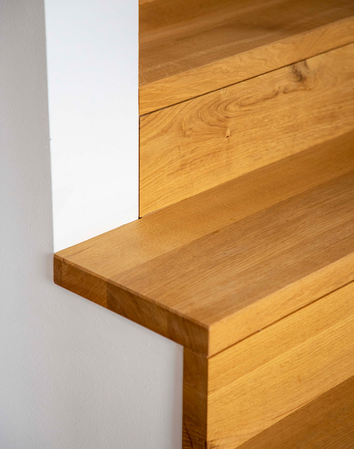 Detail einer hölzernen Treppe im Holzhaus in Neubeuern zeigt die feine Maserung und erstklassige Verarbeitung des Holzes.