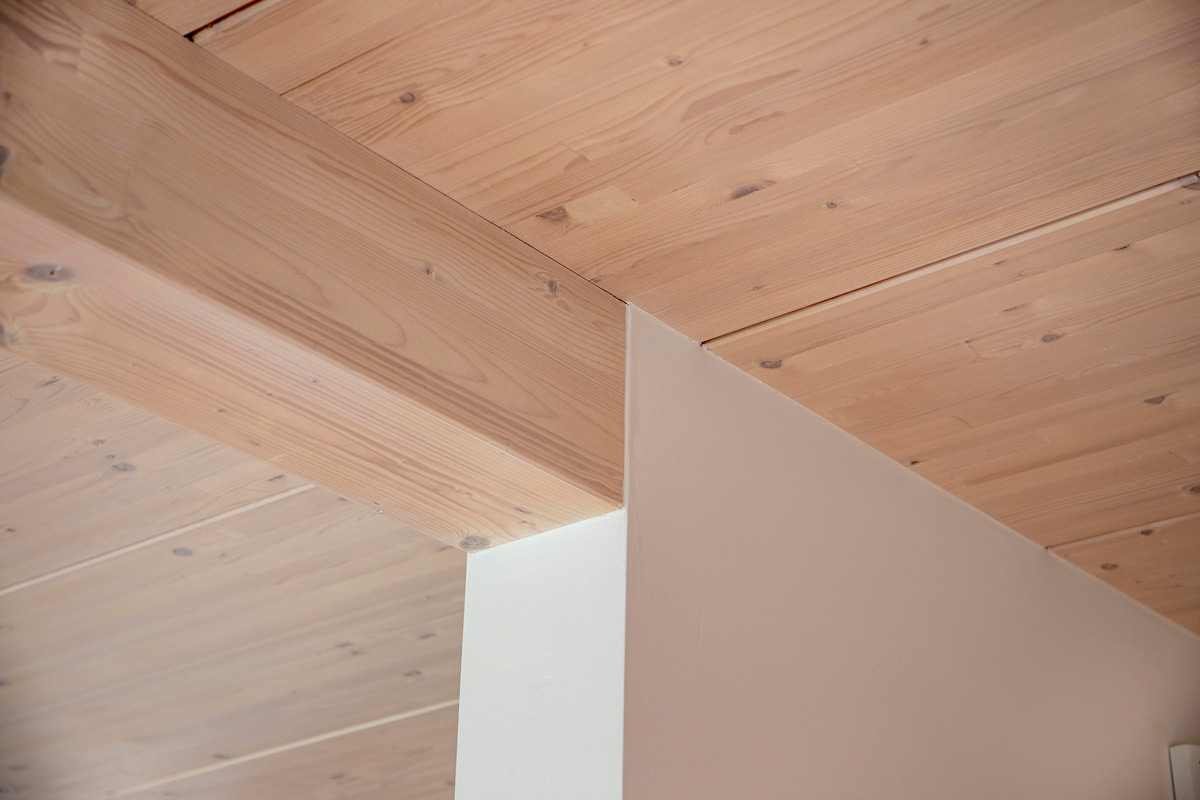 Eine Holzdecke mit sichtbaren Balken schafft in einem Haus in Chieming eine warme, natürliche Atmosphäre.