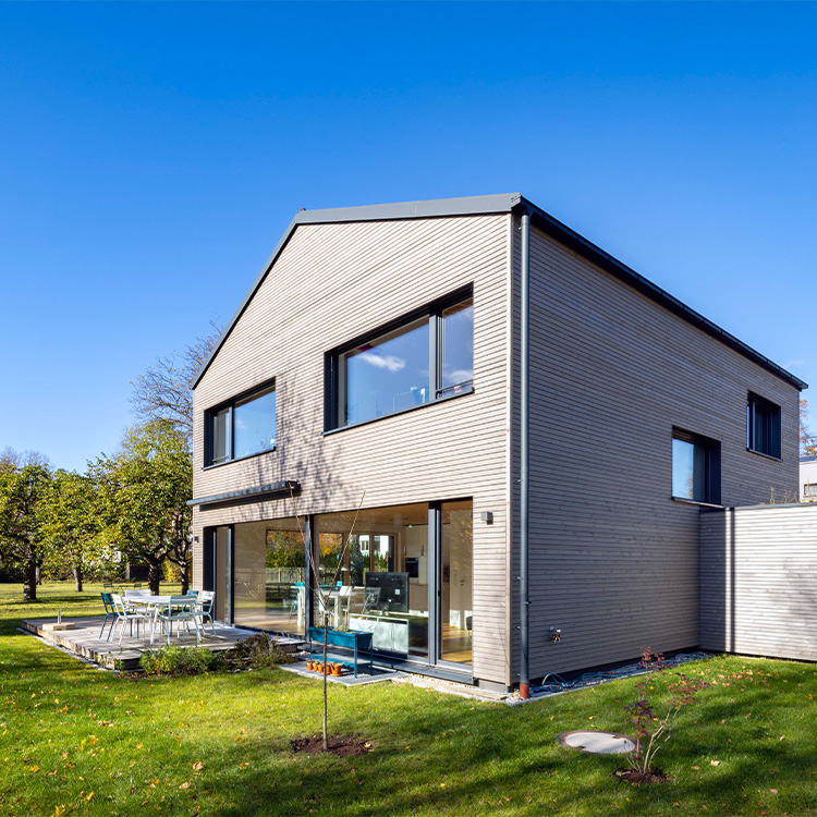 Ein modernes Holzhaus mit großen Fenstern steht in einem sonnigen Garten und ist perfekt für ein Webupdate geeignet.