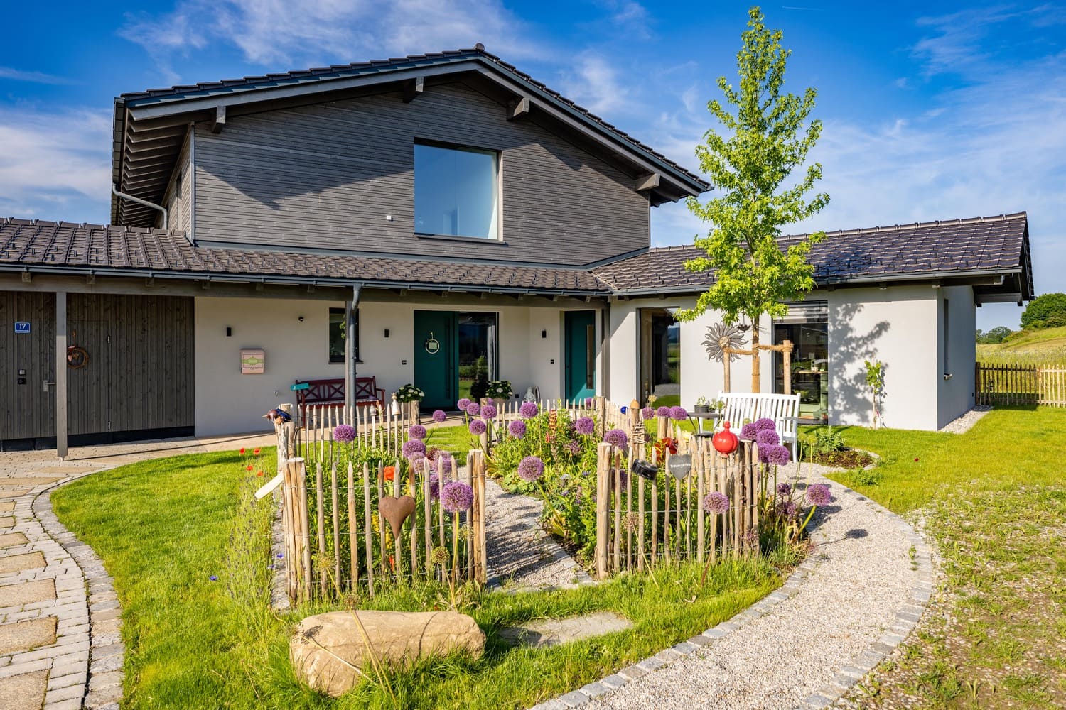 Frontansicht auf Holzhaus im Chiemgau mit Holz- und Putzfassade, Blumenbeet