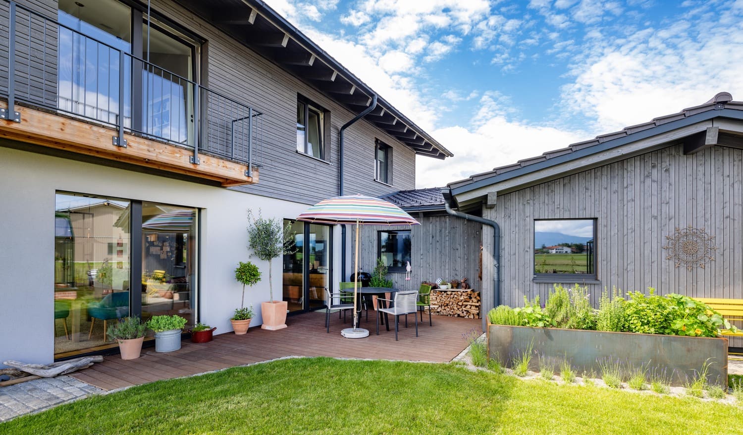 Osttrerrasse mit Hochbeet, grauen Holzfassade