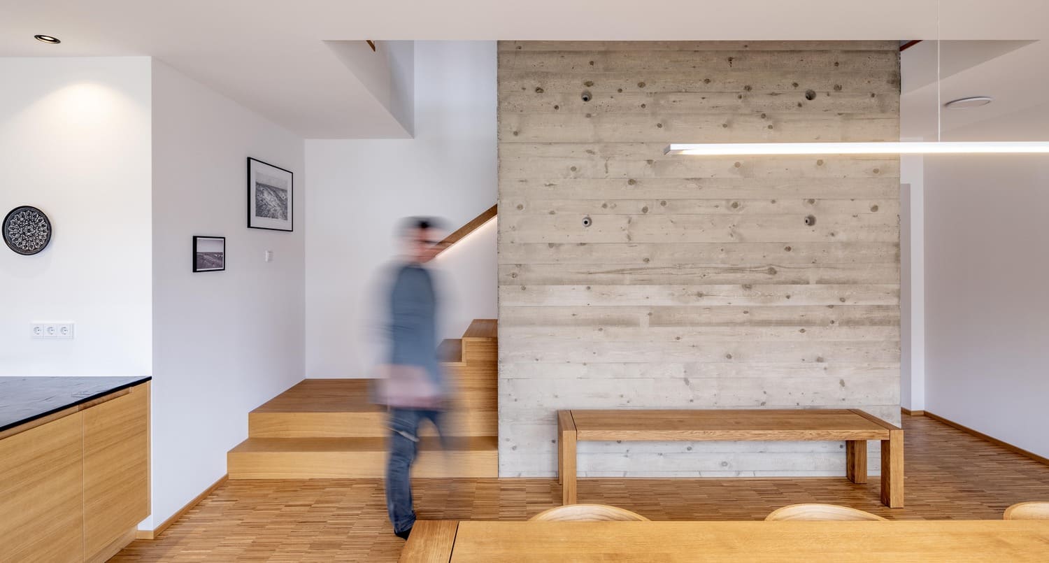 Holzbank vor Sichtbetonwand im Holzhaus