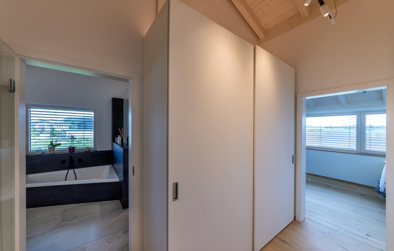 Holzhaus Weilheim Blick vom Flur in Bad und in ein weiteres Zimmer, großer Einbauschrank weiß