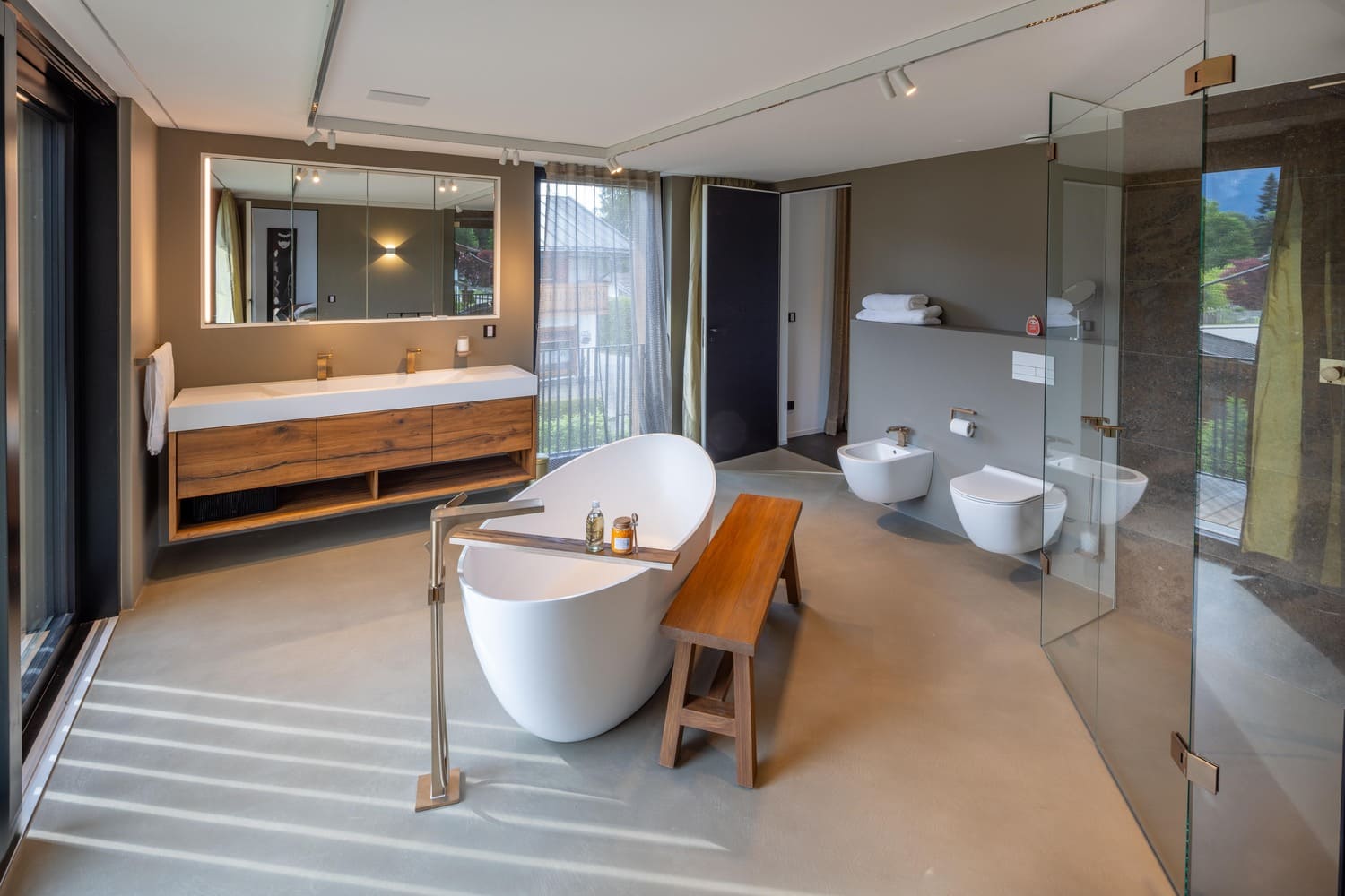 Modernes Badezimmer mit Badewanne, Holzbank, Waschbecken und eleganten Fliesen | © Name
