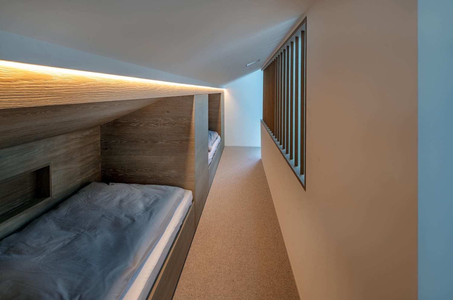 Ein minimalistischer Schlafbereich mit Holzbetten und sanfter Beleuchtung in einem modernen Raum. | © Name